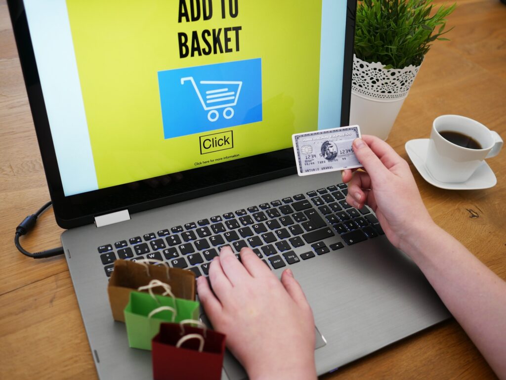 Free Shipping - Hand holding a credit card next to a laptop checkout screen with small shopping bags nearby