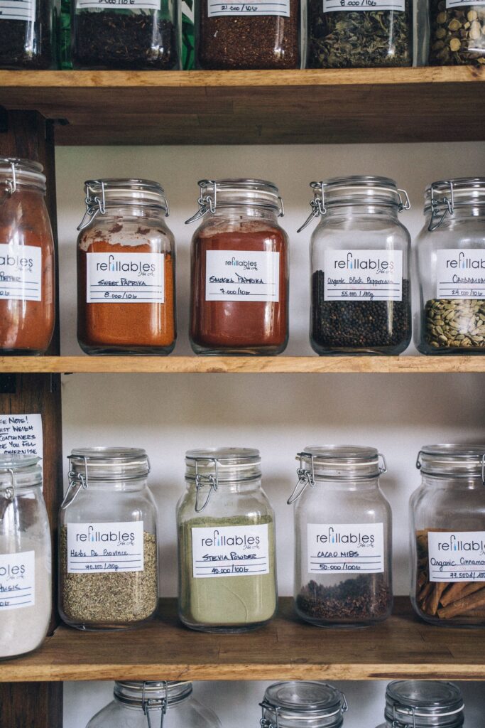 Glass jars of spices and pantry staples labeled on wooden shelves