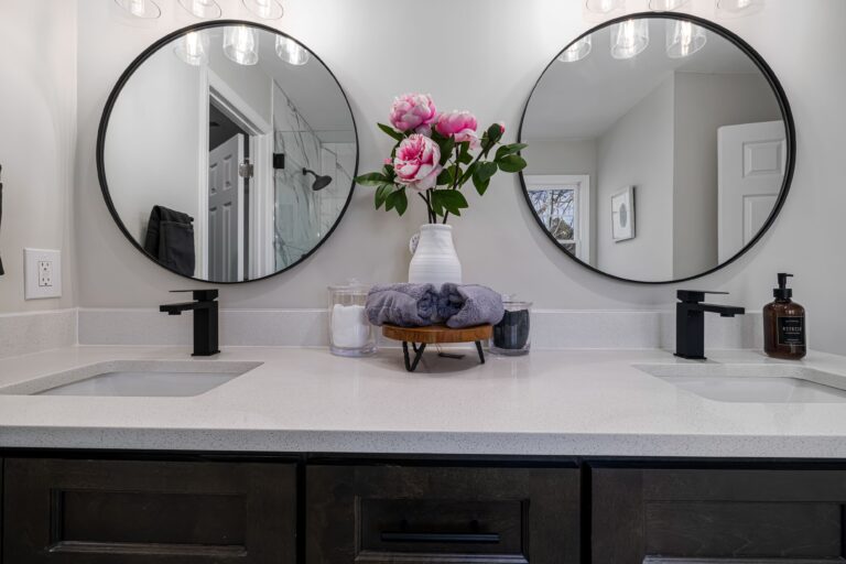 Bathroom double vanity with round mirrors, matte black faucets, and dark cabinet hardware
